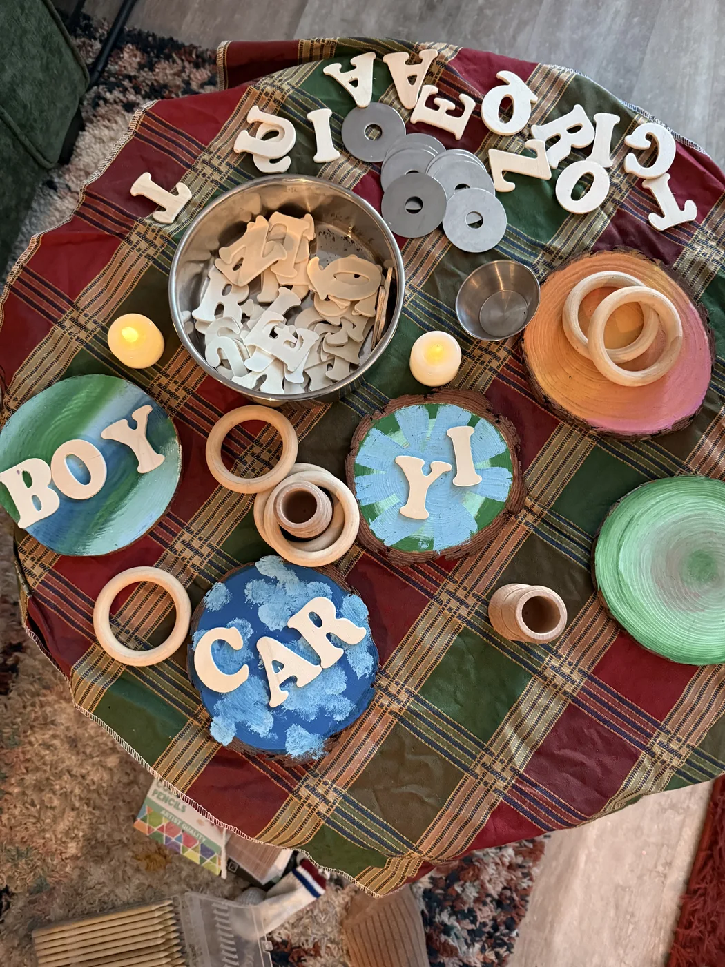 Wooden letters, rings, and name cards arranged on a table as a literacy provocation