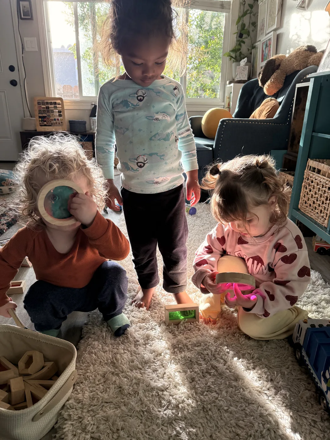Toddlers playing with wooden toys on a sunlit rug
