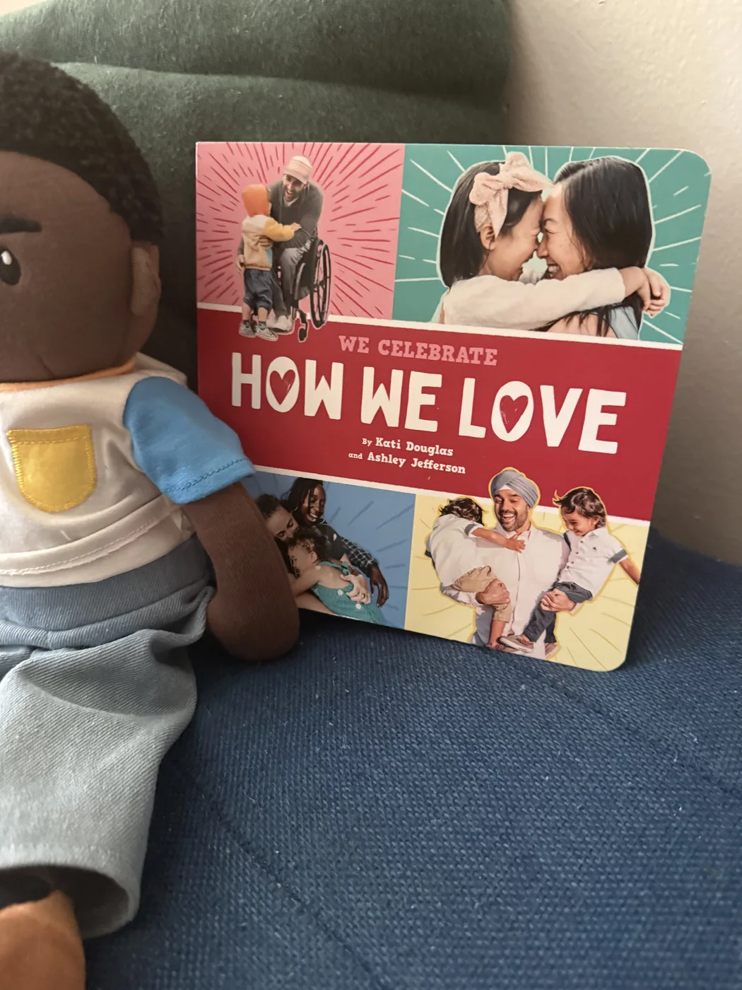 A board book titled How We Love propped beside a soft doll